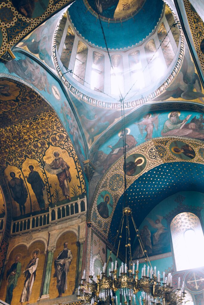 From below interior decorations of orthodox Tbilisi Sioni Cathedral with majestic chandelier hanging from ceiling decorated with icons and fresco paintings